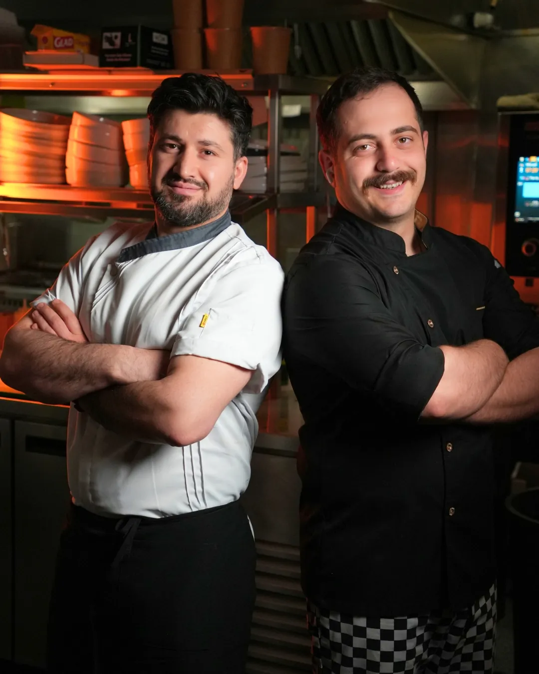 Two chefs standing back to back in the kitchen