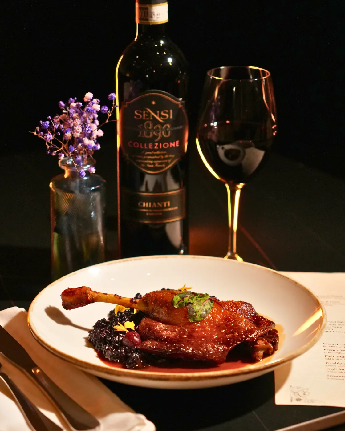 Duck confit on black rice with a bottle of Chianti and a glass of red wine